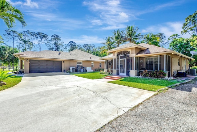 view of front facade featuring concrete driveway, a front yard, stucco siding, a sunroom, and an attached garage