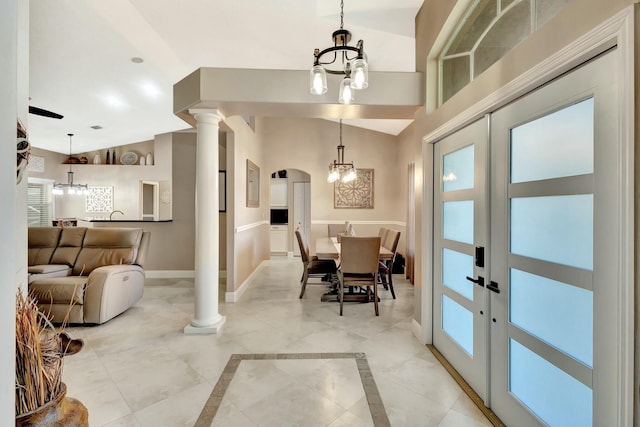 dining space with arched walkways, a notable chandelier, high vaulted ceiling, and baseboards