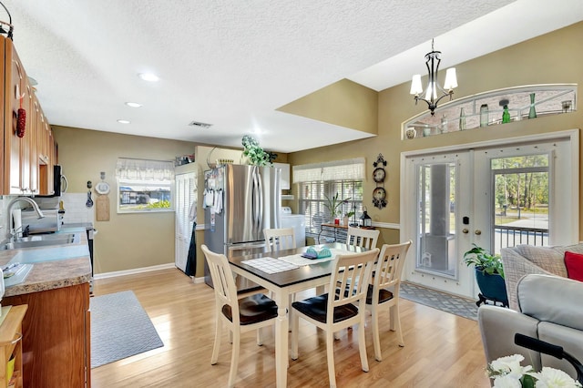 dining space featuring baseboards, plenty of natural light, a notable chandelier, and light wood-style flooring