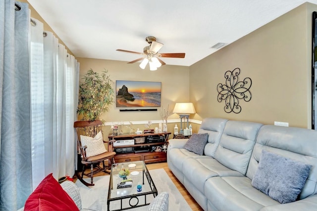 living room featuring light wood-style flooring, visible vents, and ceiling fan