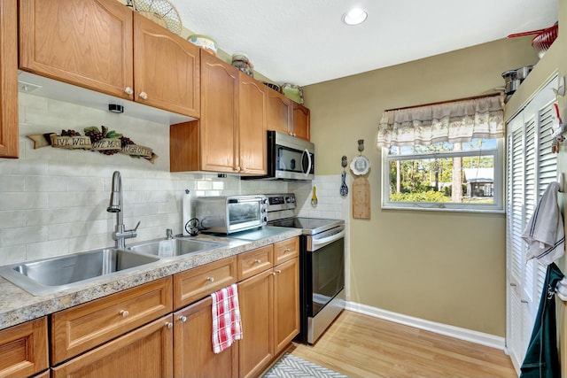 kitchen featuring a sink, backsplash, stainless steel appliances, a toaster, and light countertops