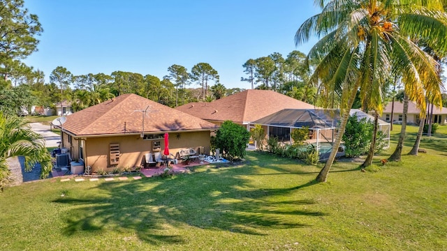 back of house with a lanai, stucco siding, cooling unit, a lawn, and a patio