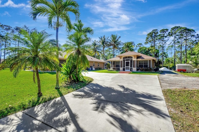 view of front facade with curved driveway, a front yard, and a sunroom