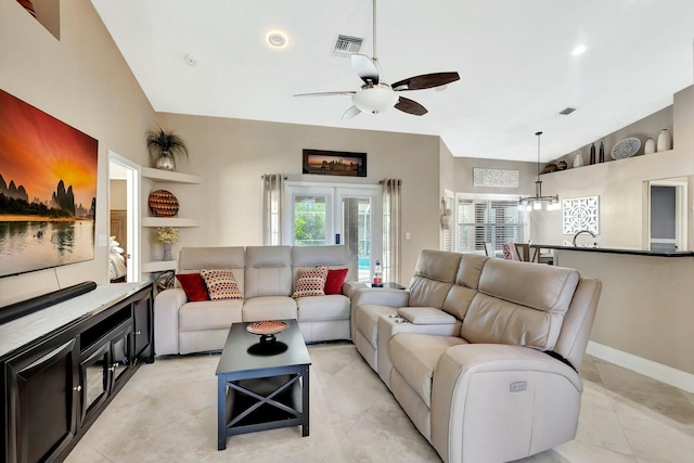 living area with light tile patterned floors, visible vents, baseboards, lofted ceiling, and ceiling fan with notable chandelier