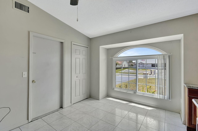 5489 NW Evanston Ave, Port Saint Lucie, FL 34983 - unfurnished bedroom with a closet, a ceiling fan, light tile patterned floors, a textured ceiling, and vaulted ceiling