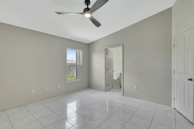 5489 NW Evanston Ave, Port Saint Lucie, FL 34983 - unfurnished bedroom featuring a textured ceiling, light tile patterned floors, baseboards, lofted ceiling, and ensuite bath
