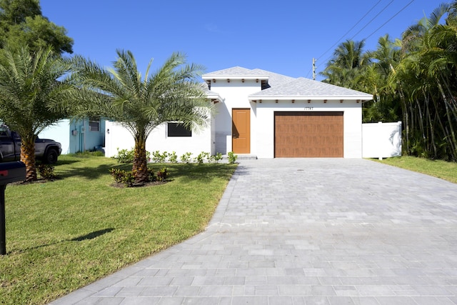 view of front facade featuring stucco siding, a front yard, decorative driveway, and a garage