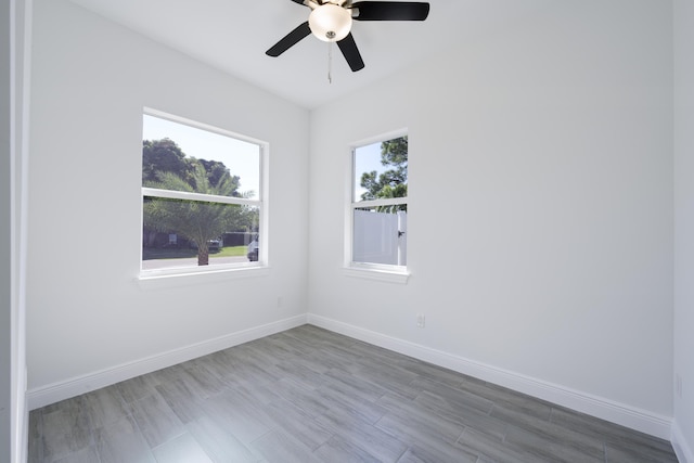 unfurnished room featuring a ceiling fan, wood finished floors, baseboards, and a wealth of natural light