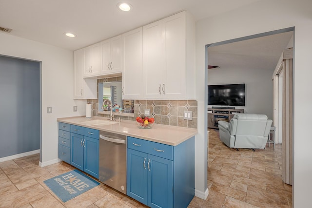 kitchen with blue cabinets, a sink, stainless steel dishwasher, backsplash, and white cabinets