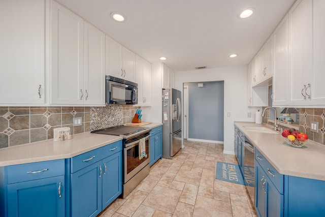 kitchen with visible vents, white cabinets, stainless steel appliances, blue cabinets, and a sink