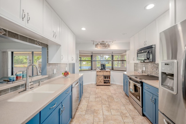 kitchen with white cabinets, blue cabinets, appliances with stainless steel finishes, and a sink