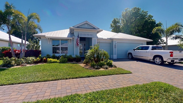 view of front of house with a garage, decorative driveway, metal roof, and a front lawn