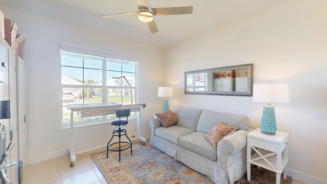 tiled living area with a ceiling fan and baseboards