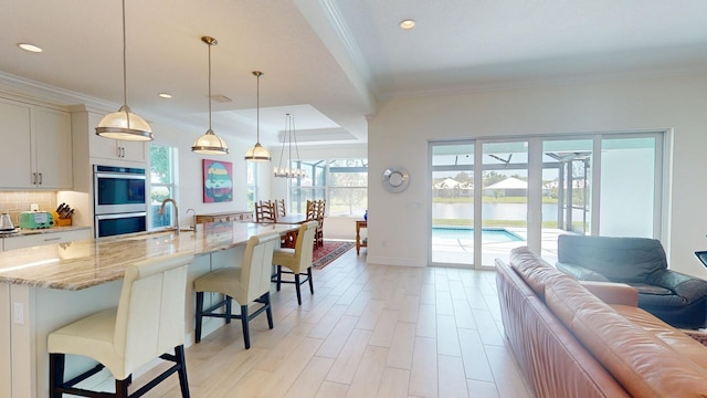 kitchen with ornamental molding, tasteful backsplash, open floor plan, stainless steel double oven, and light stone countertops