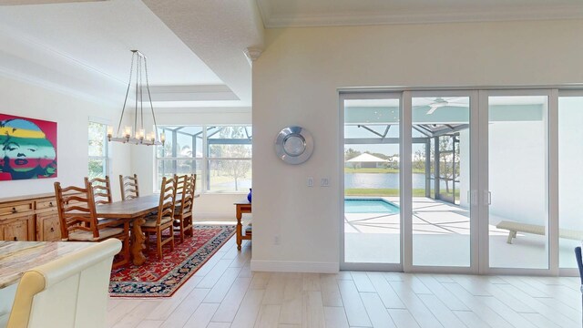 dining area with light wood finished floors, baseboards, a tray ceiling, ornamental molding, and an inviting chandelier