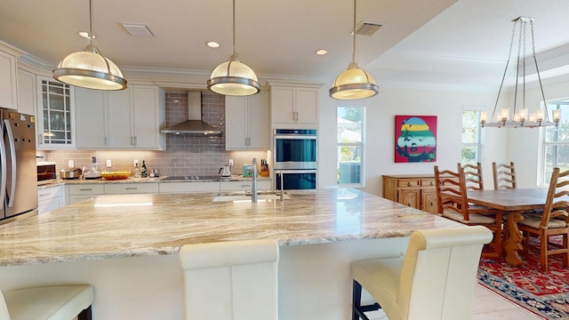 kitchen featuring wall chimney exhaust hood, visible vents, backsplash, and stainless steel appliances