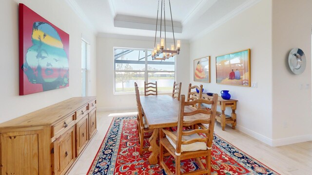 dining space with a notable chandelier, baseboards, a tray ceiling, and ornamental molding