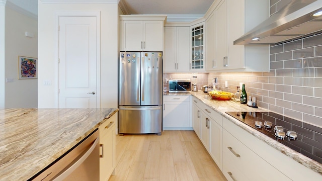 kitchen featuring stainless steel appliances, exhaust hood, decorative backsplash, and light wood-style flooring