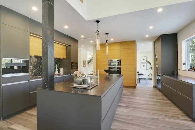 kitchen featuring light wood-style floors, decorative backsplash, dark countertops, and modern cabinets