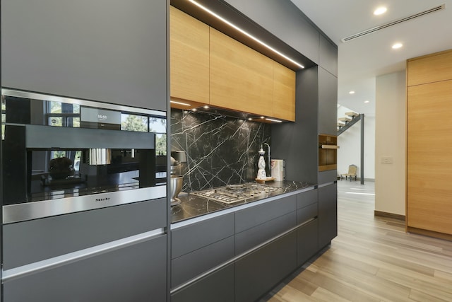 kitchen featuring stainless steel oven, backsplash, dark countertops, and modern cabinets