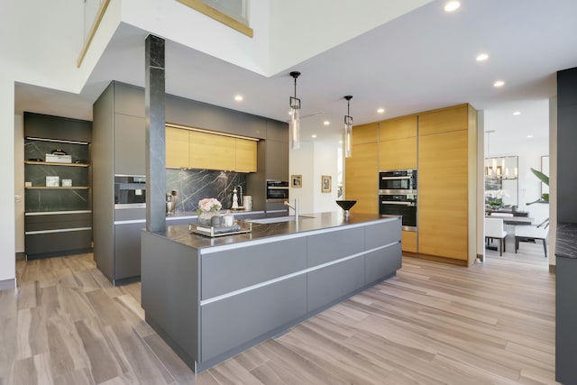 kitchen featuring a sink, decorative backsplash, double oven, modern cabinets, and light wood-type flooring