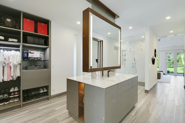 spacious closet with light wood finished floors, french doors, and a sink