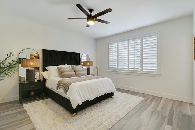 bedroom with ceiling fan, baseboards, and light wood-style floors