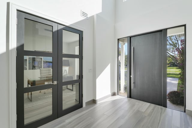 foyer entrance featuring wood finished floors, visible vents, french doors, and baseboards