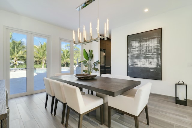 dining room featuring light wood-style flooring, recessed lighting, french doors, and a chandelier