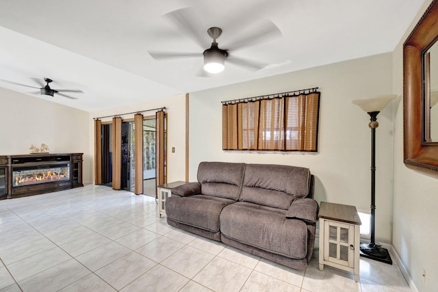 living room with a glass covered fireplace, light tile patterned floors, a ceiling fan, and baseboards