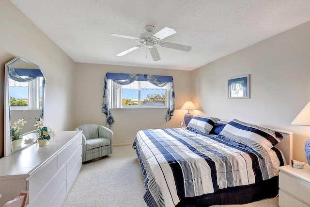 carpeted bedroom featuring multiple windows, a textured ceiling, and a ceiling fan