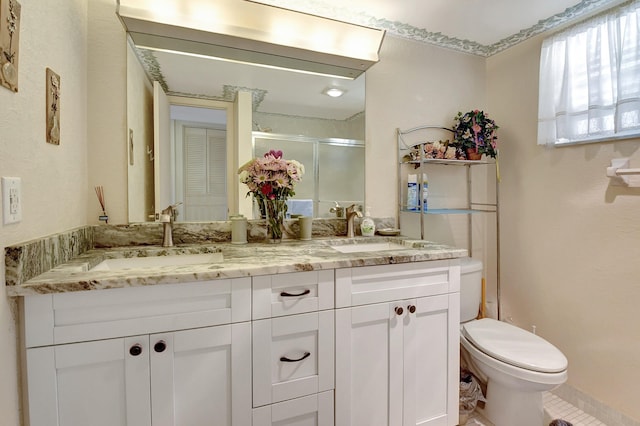 bathroom with a sink, toilet, double vanity, and a shower stall