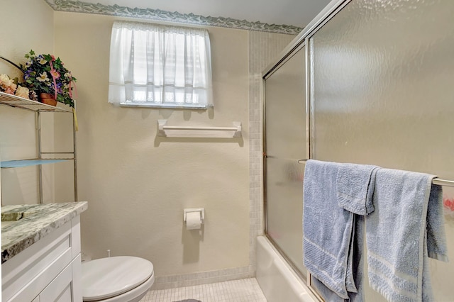 bathroom featuring vanity, baseboards, tile patterned floors, toilet, and combined bath / shower with glass door