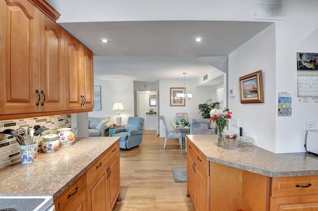 kitchen featuring visible vents, backsplash, open floor plan, light wood-type flooring, and an inviting chandelier