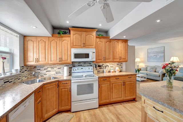 kitchen with a sink, open floor plan, white appliances, light wood-style floors, and decorative backsplash