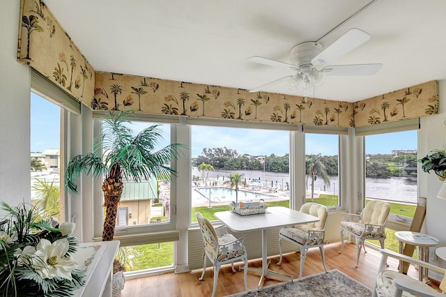 sunroom / solarium with a water view and ceiling fan