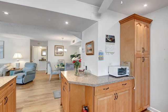 kitchen with white microwave, visible vents, light wood finished floors, an inviting chandelier, and open floor plan