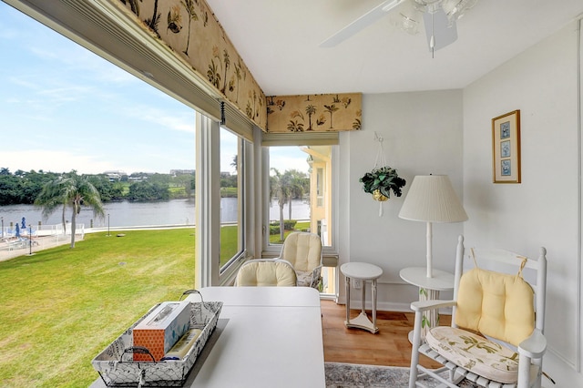 sunroom / solarium featuring ceiling fan and a water view