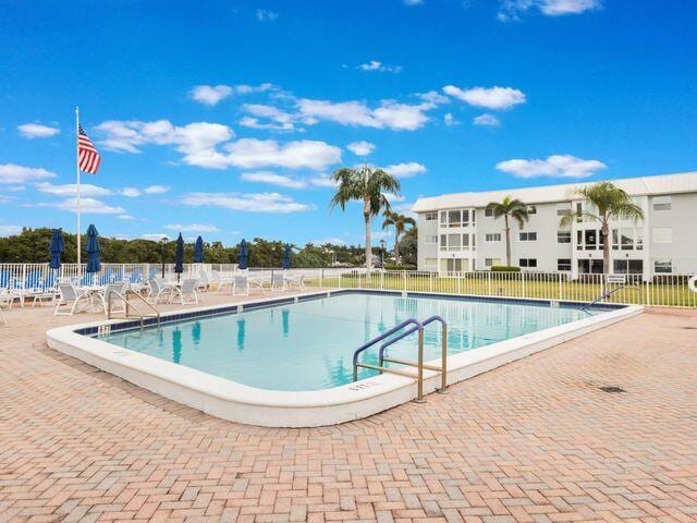 community pool with a patio area and fence