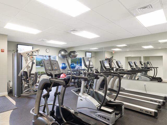 exercise room with visible vents, a paneled ceiling, and baseboards