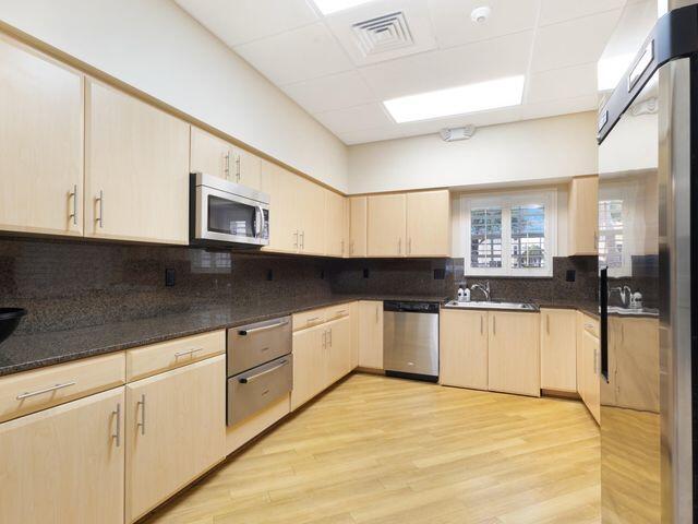 kitchen featuring visible vents, light brown cabinets, a sink, backsplash, and appliances with stainless steel finishes