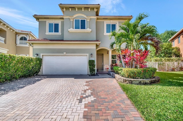 mediterranean / spanish home featuring stucco siding, decorative driveway, and fence