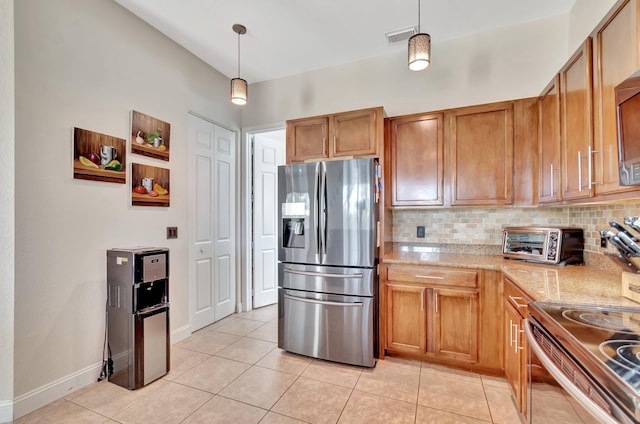 kitchen with light tile patterned floors, backsplash, stainless steel appliances, and brown cabinets