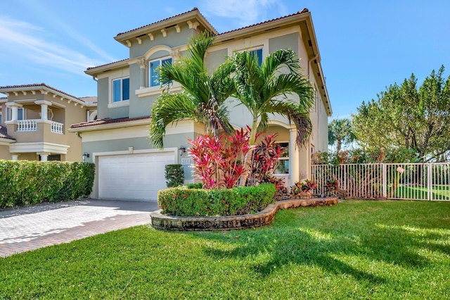 mediterranean / spanish home with fence, a front yard, stucco siding, decorative driveway, and a garage