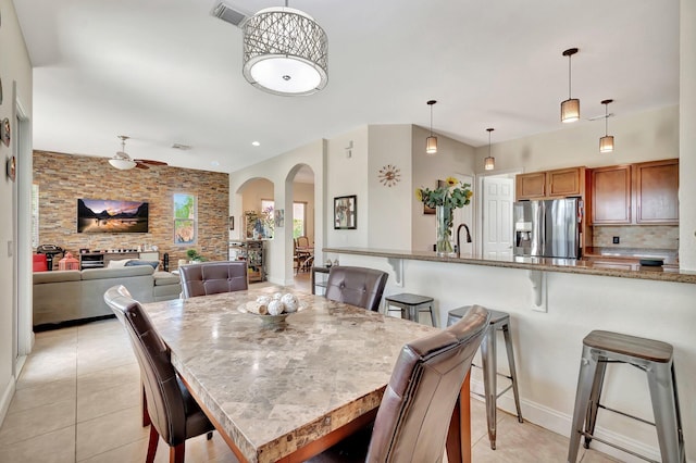 dining area with a ceiling fan, light tile patterned floors, arched walkways, and visible vents