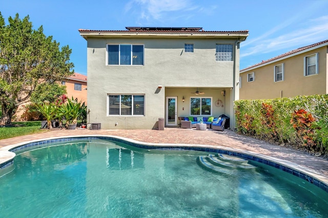 back of house featuring ceiling fan, stucco siding, outdoor lounge area, a patio area, and an outdoor pool