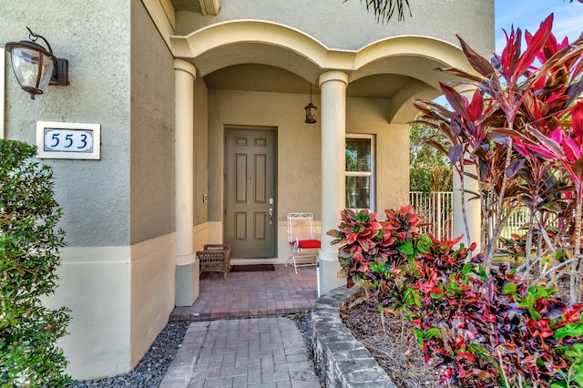 property entrance with stucco siding and fence