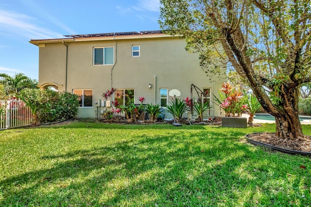 rear view of property with stucco siding, a lawn, and fence