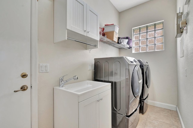 laundry room featuring baseboards, washing machine and dryer, light tile patterned flooring, cabinet space, and a sink