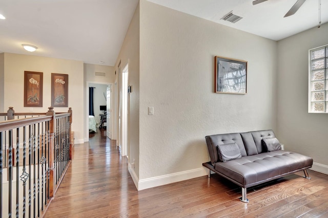 living area featuring visible vents, baseboards, light wood-style floors, and a ceiling fan